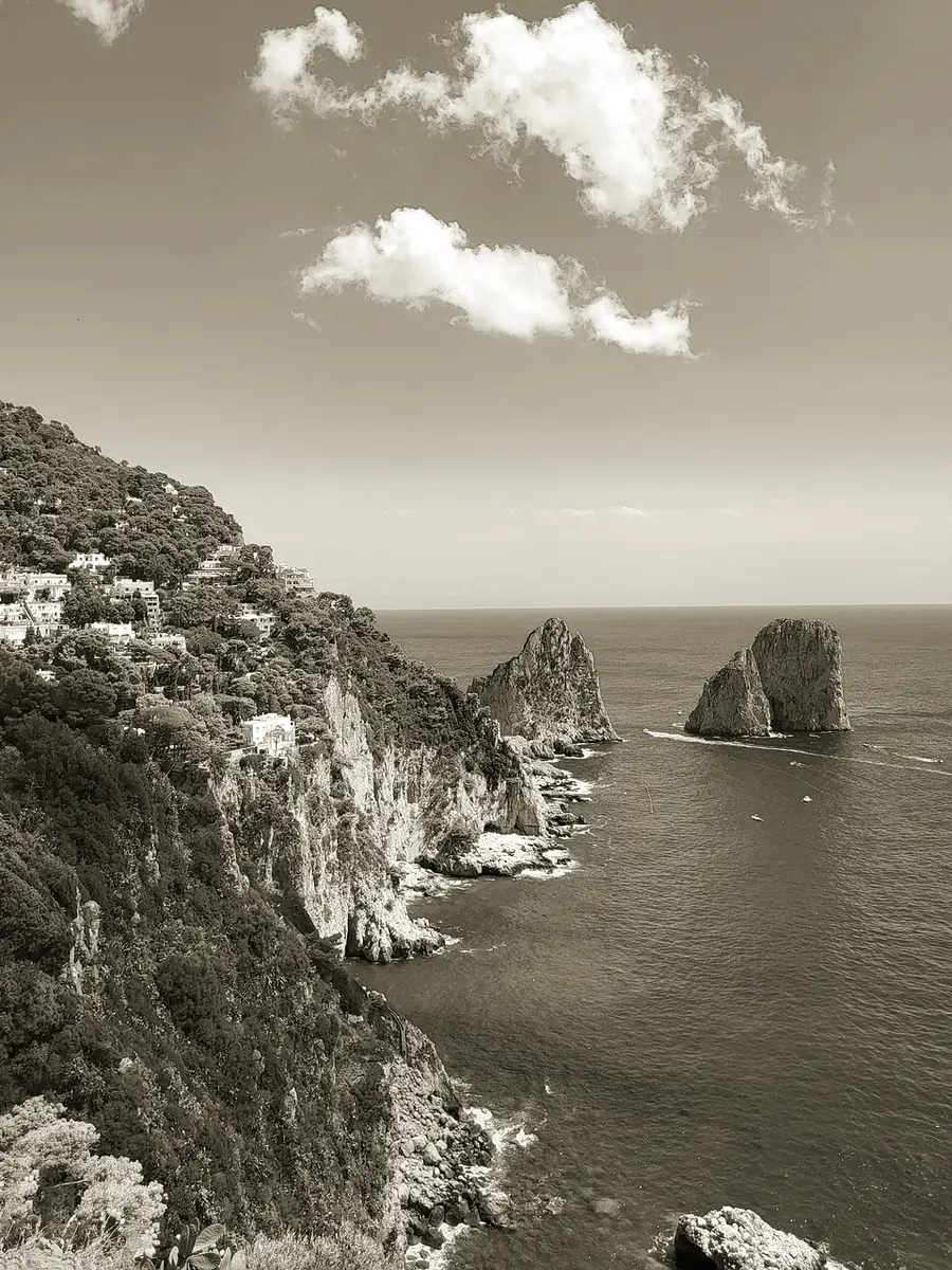 Sea cliffs and offshore rock stacks falling into deep open water under a wide sky
